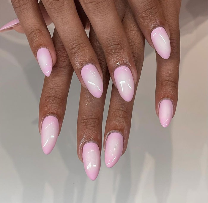 Hands with glossy pink ombre almond nails showcasing one of the top almond nails trends for 2025.