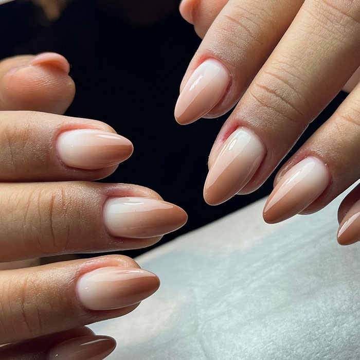 Glossy almond nails with a smooth gradient in n**e tones showcasing popular almond nails trends for 2025.