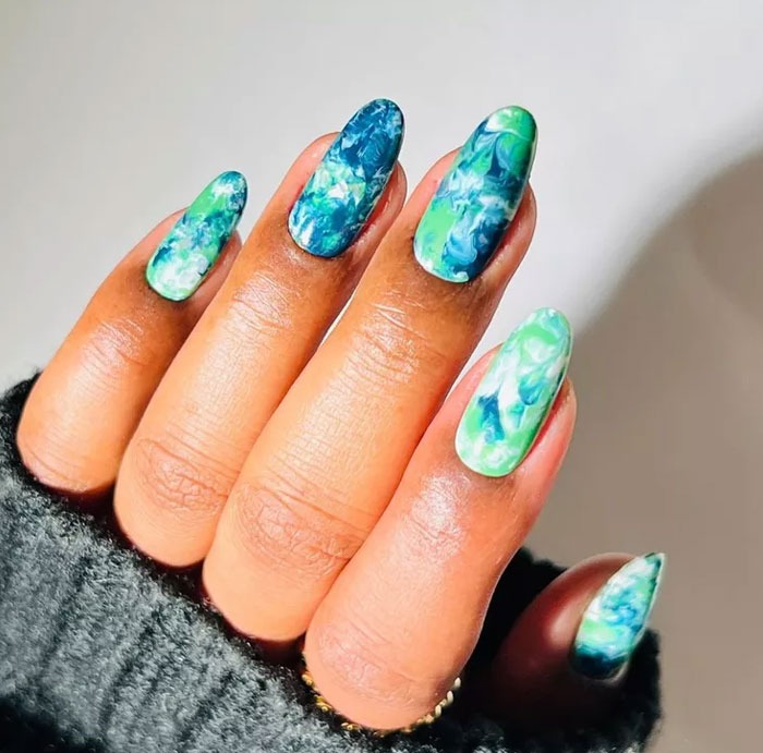 Almond nails with blue and green marble design on long nails, showcasing popular almond nails trends for 2025.