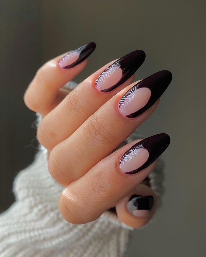 Close-up of almond nails with black and n**e abstract design, showcasing trendy almond nails style for 2025.