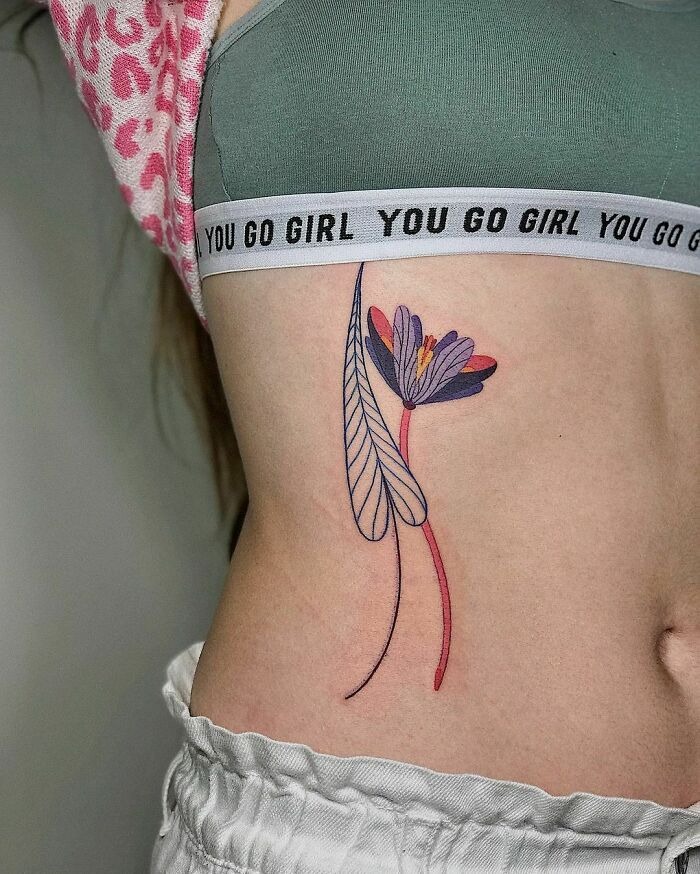 A floral tattoo on the ribcage, showcasing intricate colors and lines that appear to blossom on the skin.