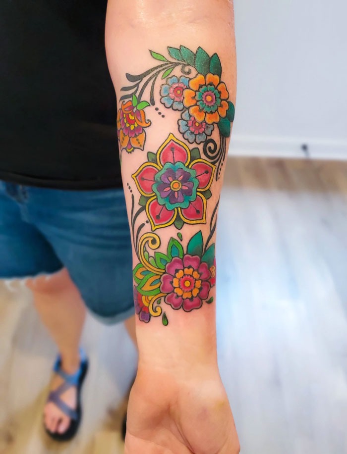 Colorful flower tattoos on arm, showcasing intricate blooming designs on skin.