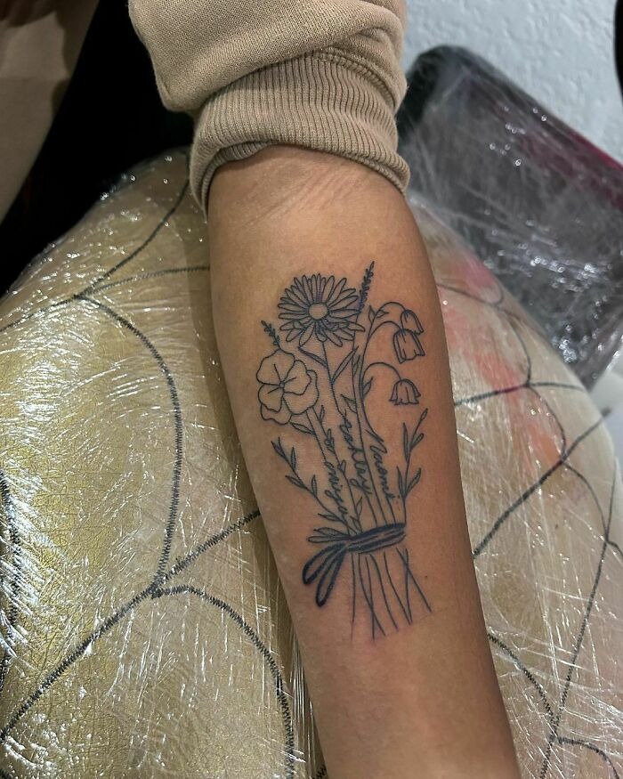 Floral tattoo with daisies and other blooms on forearm, creating a blossoming skin effect.