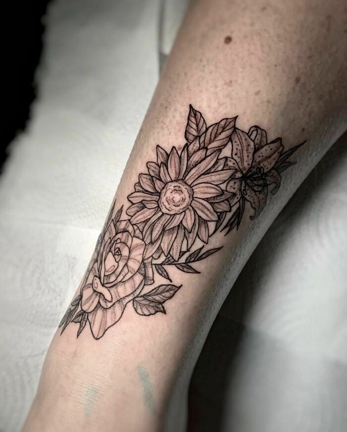 Floral tattoo with intricate blossoms and leaves on skin.