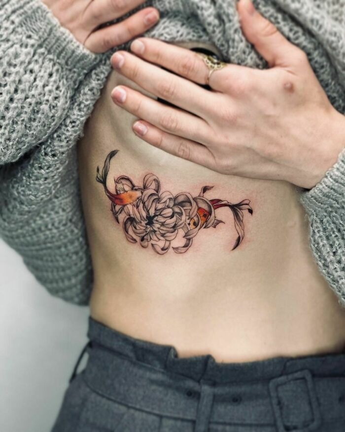 Floral tattoo on a person's side, featuring delicate flowers and leaves, creating a blossoming appearance.