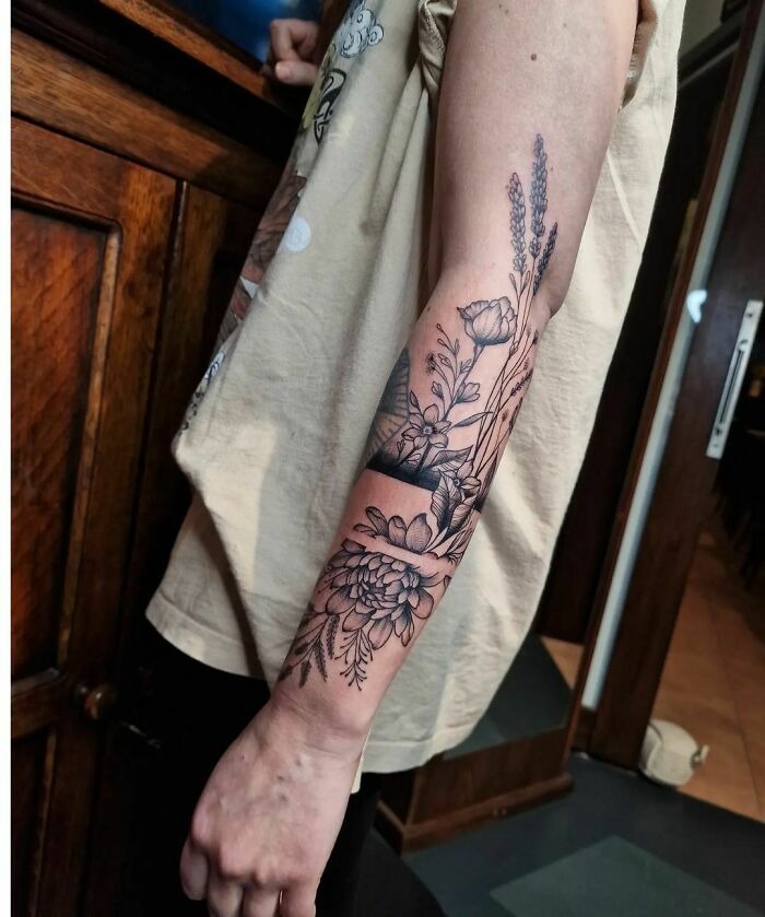Arm adorned with intricate flower tattoo, showcasing detailed floral designs.