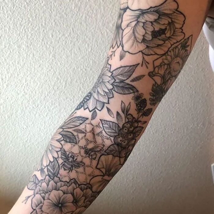 Flower tattoos with intricate designs on an arm, showcasing blooms and leaves.