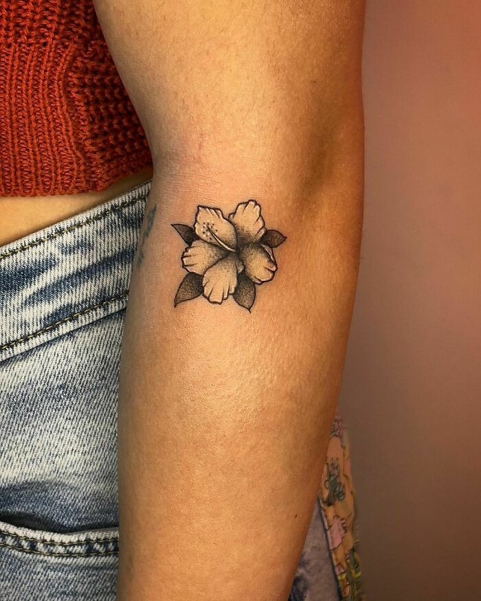 A delicate flower tattoo on the forearm, appearing to naturally blossom on the skin.