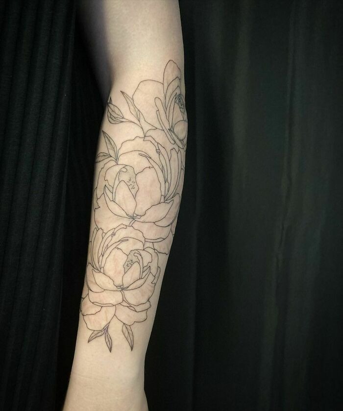 Floral tattoo sleeve design with blooming flower outlines on forearm.