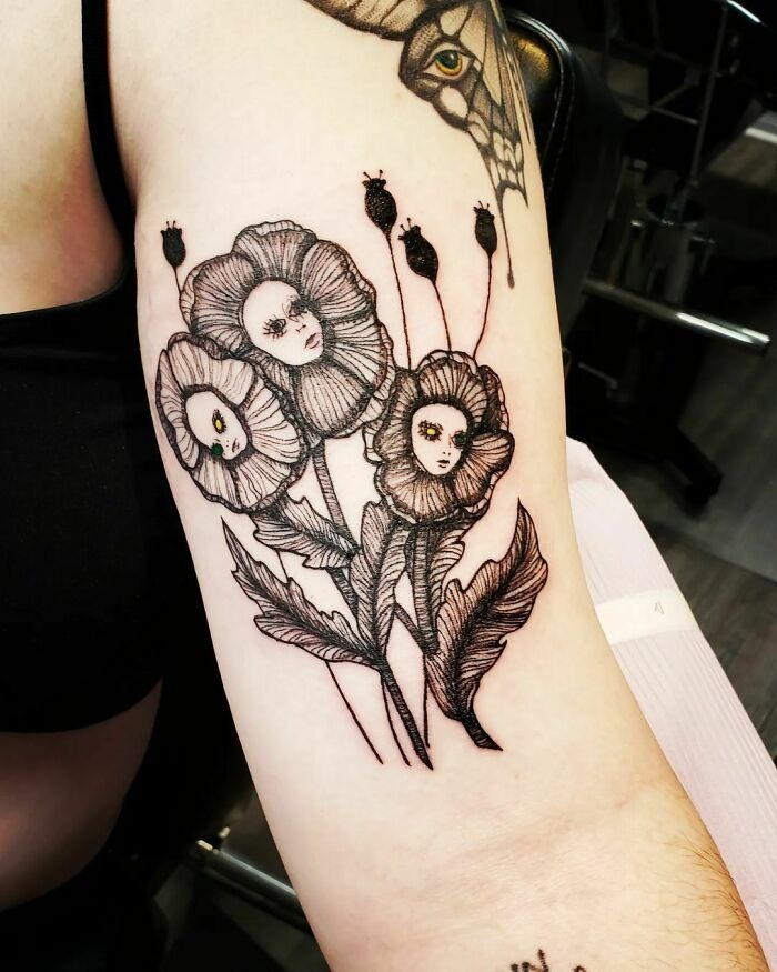 Flower tattoos with faces intricately drawn on arm, showcasing unique blossom design.